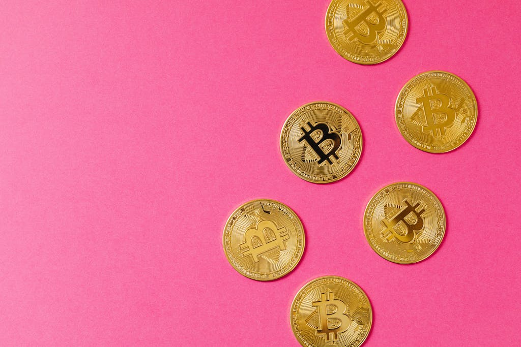 Gold Bitcoin coins on a vibrant pink surface, representing cryptocurrency and blockchain investment.